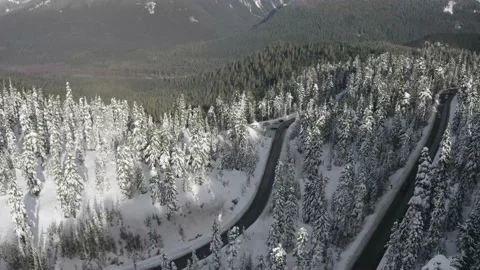 Flying over a road through a snow-covered forest in the mountains Stock Footage 197160845