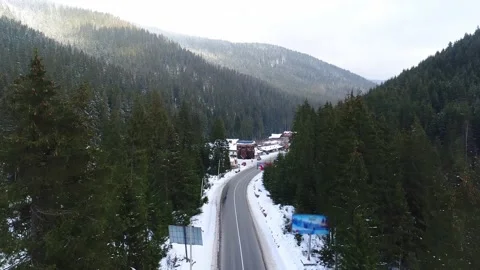 Flying over the road in winter, surrounded by green forest Stock Footage 202316547