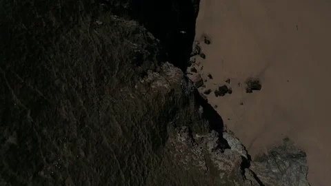 Flying over rocky cliffs and sandy beach with people walking Stock Footage 75931522