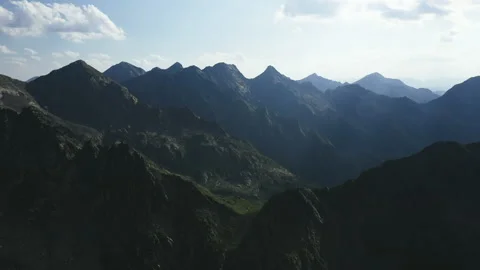 Flying over rocky mountain range into the green valley Vidéo 131385897