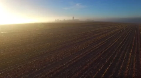 Flying over a rural farm field on scenic foggy morning Stock Footage