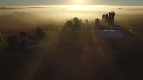 Flying over rural farms, fields, houses, on scenic foggy morning Stock Footage