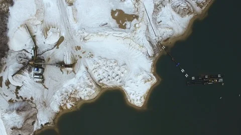 Flying over a sand extraction site covered with snow and a dark lake. Stockbeeldmateriaal 86530461