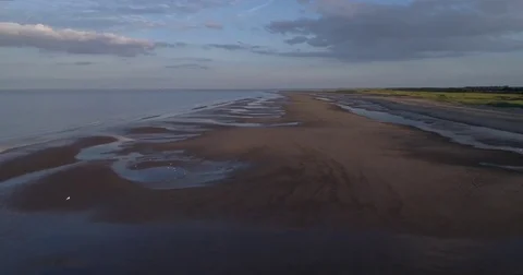 Flying over a sandy beach and sea Stock Footage 77414609
