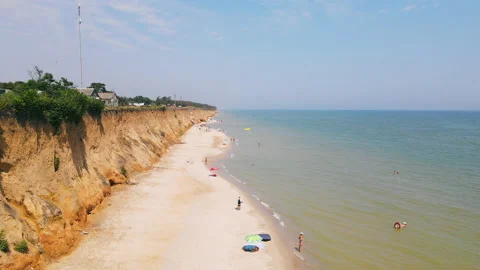 Flying over sandy beach and blue transparent water of sea, along waterfront in Stock Footage 176819842