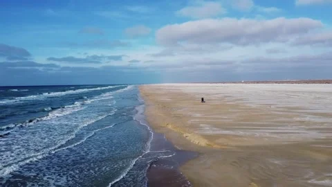 Flying over a sandy beach with beautiful waves against a blue sky with cloud Stock Footage 238894477