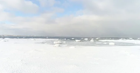 Flying over sandy beach with rolling waves and drifting ice floes in winter sea. Stock Footage 86476141