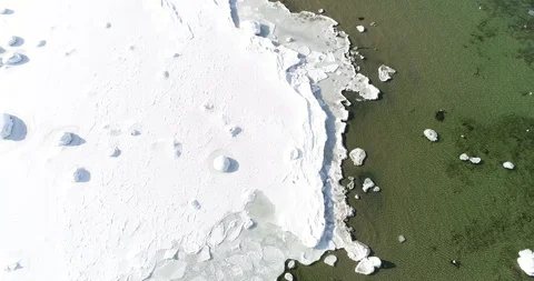 Flying over sandy beach with rolling waves and drifting ice floes in winter sea. Stock Footage 86476643