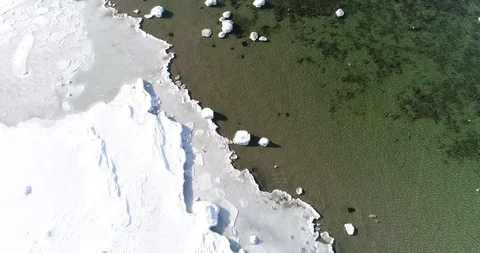 Flying over sandy beach with rolling waves and drifting ice floes in winter sea. Stock Footage 86476723