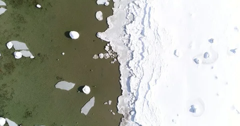 Flying over sandy beach with rolling waves and drifting ice floes in winter sea. Stock Footage 86477664