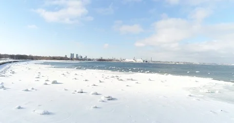 Flying over sandy beach with rolling waves and drifting ice floes in winter sea. Stock Footage 86478094