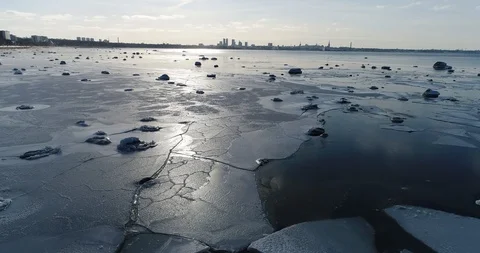 Flying over sandy beach with rolling waves and drifting ice floes in winter sea. Stock Footage 86698901