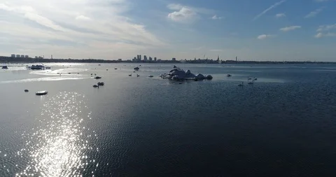 Flying over sandy beach with rolling waves and drifting ice floes in winter sea. Video stock 86699281