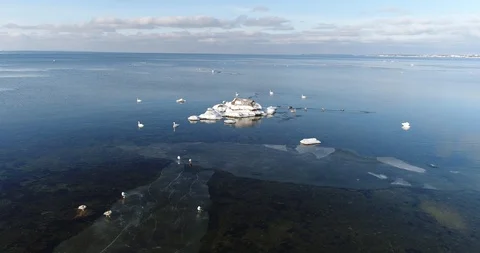 Flying over sandy beach with rolling waves and drifting ice floes in winter sea. Video stock 86699789