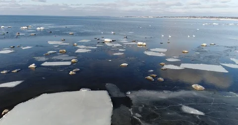 Flying over sandy beach with rolling waves and drifting ice floes in winter sea. Stock Footage 86701566