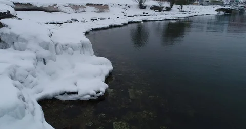 Flying over sandy beach with rolling waves and drifting ice floes in winter sea. Stock Footage 86897867