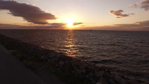 Flying over sea and coastline at sunset, aerial view Stock Footage