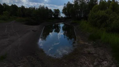 Flying over a small backwater in a shallow riverbed, surrounded by bushes, .. Photos