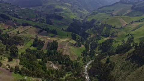 Flying over a small mountain river surrounded by agriculture fields and roads Stock Footage 169959598