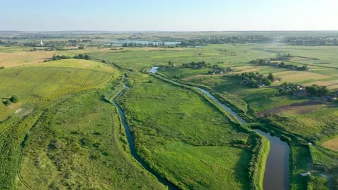 Flying over a small river and a green field Stock Footage 161827671