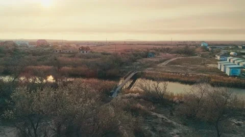 Flying over a small river and bridge on an autumn evening at sunset Stock Footage 209425662