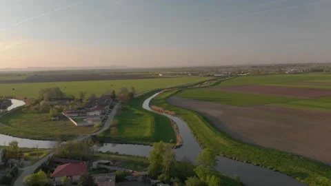 Flying over a small river and rural vilage in the sunset Stock Footage 232486907