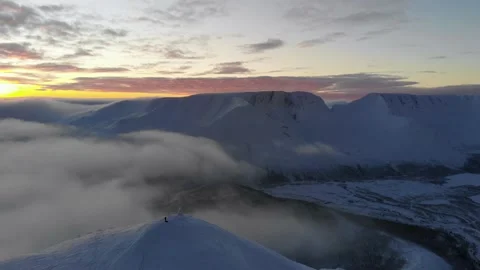 Flying over snow-capped mountains in the clouds at sunset. Aerial view. Colorful Video stock 152588401