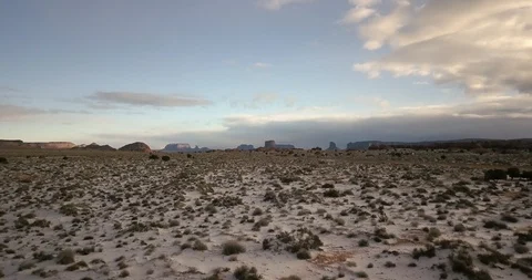 Flying over snow-covered desert floor and sagebrush in Monument Valley Stock Footage 106482591