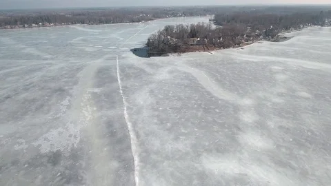 Flying over snow covered houses along frozen icey lakefront, Michigan USA Stock Footage 128404585
