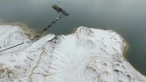 Flying over a snow covered quarry and a dark water lake. Stock Footage 86525644