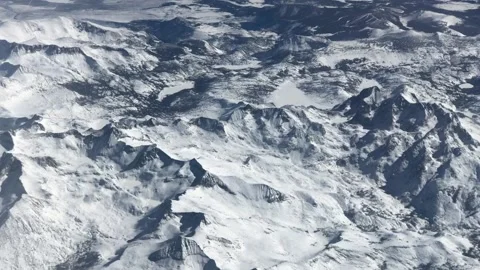 Flying over the snow covered sierra nevada mountian range in California Stock Footage