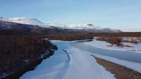 Flying over snow patch covered river shore with clean cold melting water Stock Footage 156495931