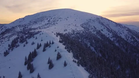 Flying over a snowy mountain in winter nature at sunset, aerial view from above 스톡 동영상 230095448