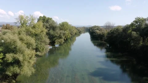 Flying over straight, calm river Kolpa reflecting a bright blue sky with forest. Stock Footage 285771928