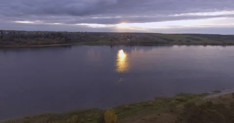 Flying over the sunset river overlooking a small village on the shore Stock Footage 85674055