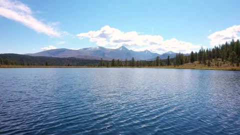 Flying Over Surface Of Blue Lake Against The Backdrop Of Snowy Mountains Summits Stock Footage 167754728