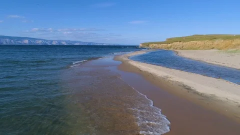 Flying over the surface of the blue water and the shore of lake Baikal Stock Footage 121925325