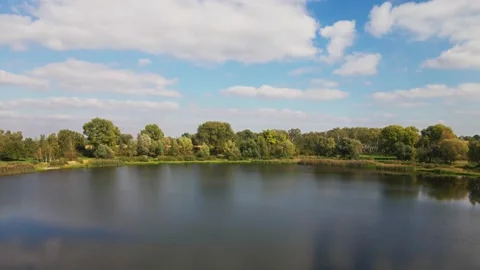 Flying over the surface of a small round lake on a sunny day. Stock Footage 168564374