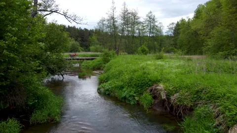 Flying over tight clean river revealing motorcycle standing on bridge Stock Footage 169928643