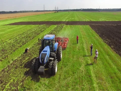 Flying Over Tractor Plowing Ground on Green Field Stock Footage 73717497