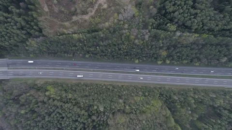 Flying over a traffic highway surrounded with green colorful spruce forest, 4K Stock Footage 74467953