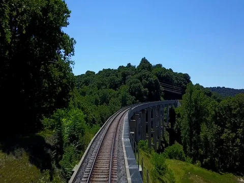 Flying over train tracks and bridge on bright sunny day. Vídeo Stock 79428365