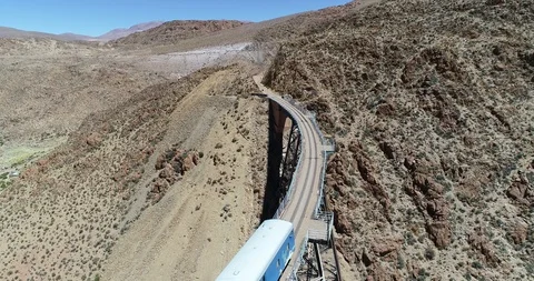 Flying over train while it drives through old metal bridge at a desert landscape 스톡 동영상 107214481