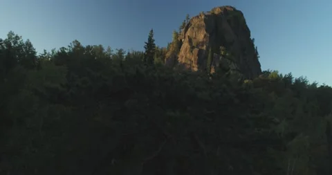 Flying over trees in forest overlooking high cliff Stock Footage 166894372