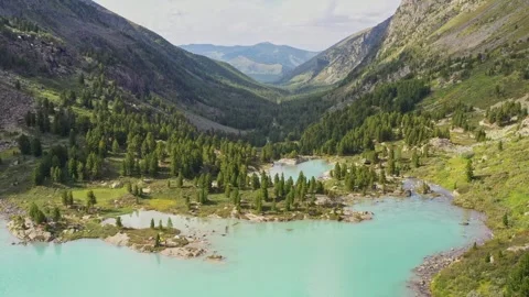 Flying over a turquoise lake and a valley overgrown with forest between the Stockbeeldmateriaal 264510941