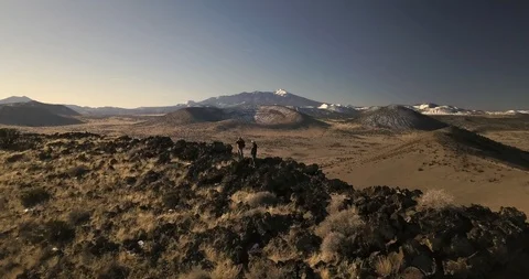 Flying over two photographers standing on the rim of a desert crater Stock Footage 106483189