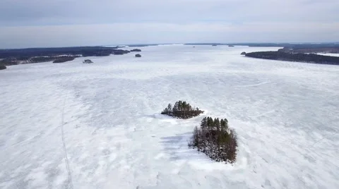 Flying over two small islands at a frozen lake Stock Footage 62434214