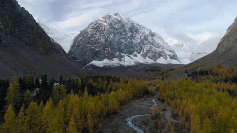 Flying over valley with autumn trees and river among high mountains Stock Footage 123700927