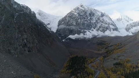 Flying over valley with autumn trees and river among high mountains Stock Footage 123701847