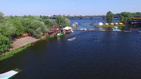 Flying over wakeboarding cable wake park HD aerial video Wakeboarder jump tricks Stock Footage 79242174